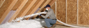 A technician installing blown-in insulation into an attic's floor
