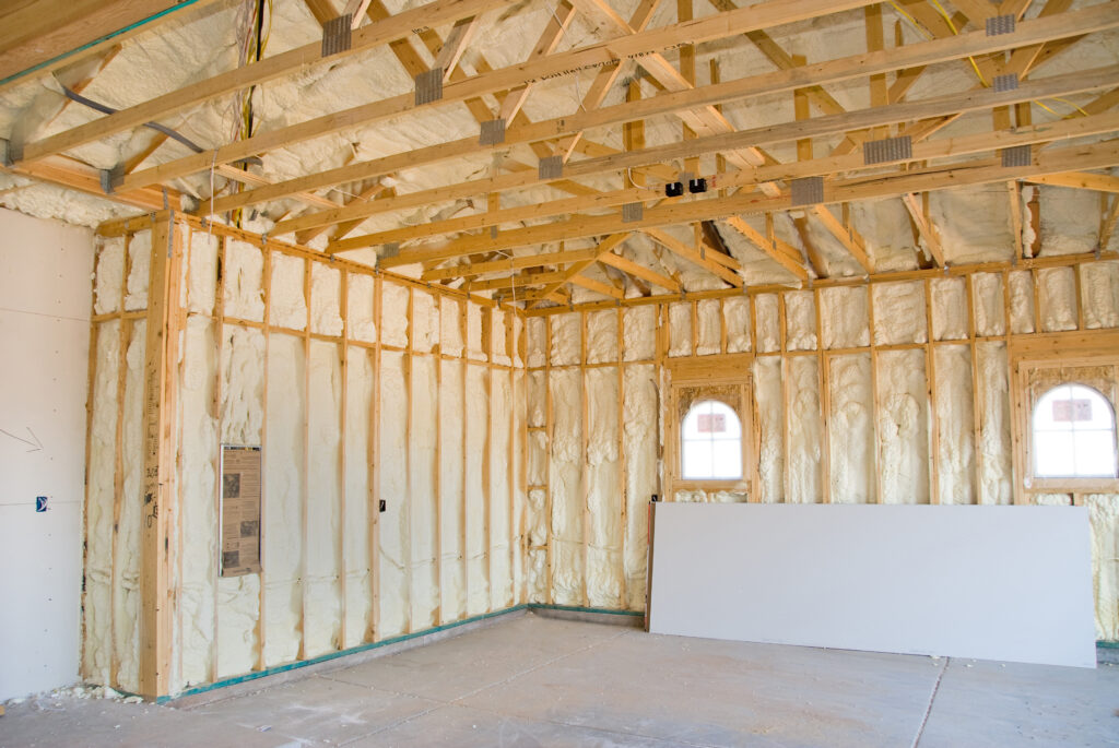 A room at a newly constructed home is sprayed with liquid insulating foam before the drywall is added.  Ideal for new home construction advertising and other home construction promotional inferences.